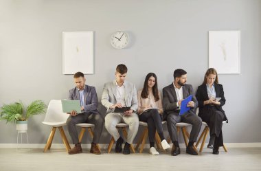 Genç insan kaynakları başvuru sahipleri sırada oturup ofiste önemli bir röportaj için hazırlanıyorlar, boş adaylar ellerinde özgeçmiş bulunan sandalyeleri, insan kaynaklarını, işe alım ve iş aramasını bekliyorlar.