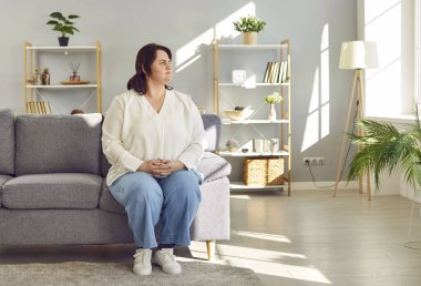 Şişman, rüya gibi bir kadının portresi artı beden bir esmer kadının günlük giysiler giyip evdeki oturma odasındaki koltukta oturması. Şişman şişman kız, düşünceli bir şekilde pencereden dışarı bakıyor..