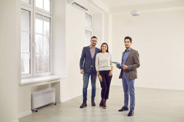 Genç mutlu çift emlakçı ile yeni bir ev arıyor. Profesyonel emlakçı parlak yeni bir daire gösterdi. Başarılı bir aile ev sahibi olmaya hazır. Emlak piyasası kavramı.