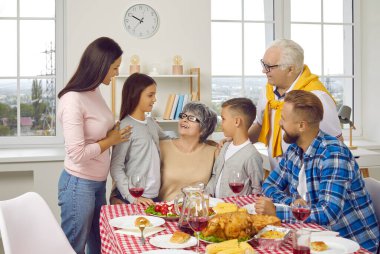 Mutlu bir aile portresi. Aileler, büyükanneler, büyükbabalar ve iki çocuk. Evdeki bayram kutlamaları sırasında bayram masasında birlikte yemek yiyorlar..