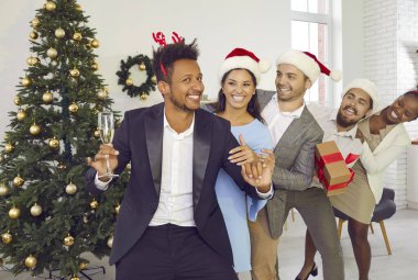 Bir grup mutlu arkadaş, süslü Noel ağacında eğleniyor. Mutlu insanlar Noel Baba şapkaları ve boynuzlu bantlar takıyor ve geyik boynuzları birbirlerinin arkasında dans ediyorlar. Noel ve Yeni Yıl Tatili