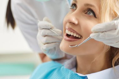 Doktor diş hekimi ya da hemşire klinikteki hastayı muayene ediyor, oral bakım için diş aleti kullanıyor, profesyonel bir atmosferde diş hekimliği ve sağlık hizmeti veriyor..