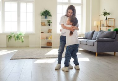 Farklı yaşlarda mutlu çocuklar oturma odasında durup birbirlerine sıcak ve şefkatle sarılıyorlar. Gülümseyen kardeş kucaklıyor, ilgi gösteriyor, yakınlık gösteriyor, duygusal bağ kuruyor ve aile bağı kuruyor.