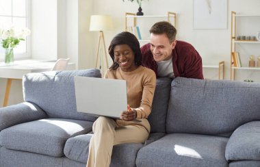 Neşeli aile çifti koltukta dinleniyor, her gün internet eğlencesine dizüstü bilgisayarla vakit geçiriyorlar. Keyif ve bağlantı dolu bir ortamda..