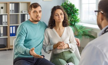 Evli bir çift, doktor jinekoloğa hamilelik ve planlama konusunda danışmanlık yapıyor, planlama kliniğinde poz veriyor. Sağlık ve tüp bebek tedavisi kavramı