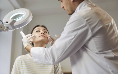 Güzellik tedavisi, kozmetik cerrahisi, güzellik uzmanı, estetik cerrah klinikteki kadın hastaya danışmanlık yapan doktor yüzlerine dokunan çekici kadın, profesyonel kozmetik bakımı, cilt bakımı, dış görünüş.