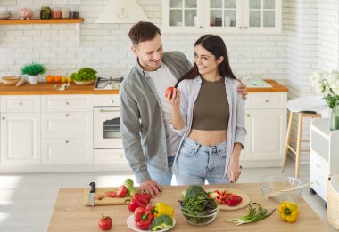 Konforlu modern mutfak evinde mutlu bir çift sağlıklı vejetaryen yeme alışkanlıklarının keyfini çıkarıyorlar, modern yerde yemek pişirme, aşçılık hobisi, yeni ev sahipleri, taşınma gününü kutluyorlar, mutlu hissediyorlar.