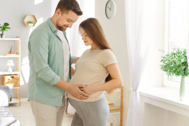 Sevgi dolu bir çift ayakta sarılıyor, müstakbel ebeveynler ilk bebeği evde bekliyor, ilgili koca ve hamile eş, sevgisini ifade ediyor, ebeveynlik, yeni hayat, planlama, hayal kurma, doğum öncesi bakım.