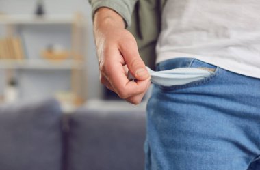 Fakir bir adamın elleri boş, açık bir cebi gösteriyor, mali sorunları, sorunları ve yoksulluğu simgeliyor. Meteliksiz, iflasın eşiğinde ve açık mali zorluklar yaşıyor..