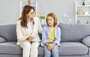 Doktor psikolog üzgün bir çocukla duygusal ve zihinsel destek sağlamak için terapi seansı düzenliyor. Üzgün çocuk, depresyon sorunlarıyla başa çıkmak için oturum sırasında yardım alıyor.