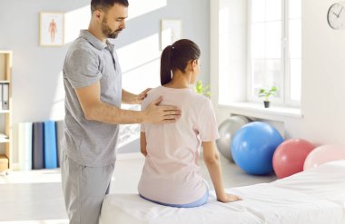 Erkek fizyoterapist ve masör bir rehabilitasyon kliniğindeki hastaya sırt masajı terapisi sağlar. Fizik tedavi, rehabilitasyon teknikleriyle iyileşme ve gerilimi arttırır..