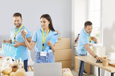 İnsani yardım merkezinde işbirliği yapan neşeli gönüllülerden oluşan bir ekip yiyecek dağıtmak ve ayırmak için birlikte çalışıyorlar. Yardım organizasyonu ihtiyacı olan insanlara temel yardım ve desteği sağlıyor..