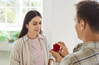 Elinde kırmızı hediye kutusu olan genç adam mutlu bir kız arkadaşa evlenme teklif ediyor. Adamın biri evinde oturan neşeli kız arkadaşına nişan yüzüğü ya da mücevherle sürpriz bir hediye veriyor..