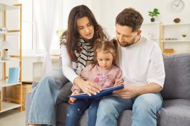 Baba, anne ve kız kitap okumaya, hikaye okumaya ve resim seyretmeye, çocuğa poz vermeye, rahat koltukta oturmaya, ev ortamının tadını çıkarmaya odaklandılar. Harika bir aile kitabı.
