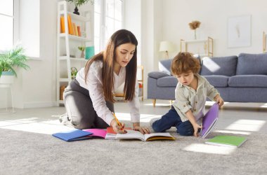 Mutlu anne ve çocuk evde boş zamanlarında birlikte çizim yaparlar, yaratıcılığa odaklı rahat bir aile ortamında öğrenme yoluyla ilham ve eğitimi teşvik ederler..