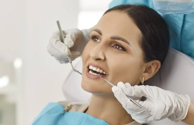 Hastane ziyareti sırasında kadın ağız bakımını kontrol eden doktor dişçi veya hemşire, sağlık ve dikkat odaklı profesyonel bir ortamda diş hekimliğine yardım ve destek sunmaktadır..