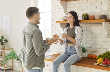 Mutlu, sevecen, genç, evli bir çift modern stil mutfağında konuşmaktan keyif alıyor. Hafta sonlarını kendi dairesinde kaygısız, boş vakit geçirmekten, sabah içkisinden ve dinlenmekten bahsediyor.