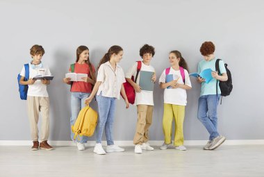 Okul çocukları, genç öğrenci arkadaşları ve sınıf arkadaşları sırt çantalarıyla duvarda yan yana duran kızlar ve oğlanlar arkadaşça eğitim ortamının, sevgi dolu takım iletişiminin, günlük kıyafetlerin keyfini çıkarıyorlar. 