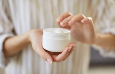 Kadın ellerinin kozmetik krem şişeleme kavanozunu tutuşu, kadın nemlendirici kremi parmağa sürüşü, el, yüz ve vücut derisine sürüşü, cilt bakımı, güzellik spa tedavisi 