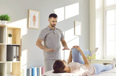 Terapist hastaya rehabilitasyon, masaj, bacak ve eklem germe egzersizlerinde yardımcı olur. Fizyoterapi seansı iyileşmeyi hızlandırıyor. Doktorun hastaların iyileşmesine olan bağlılığını gösteriyor..