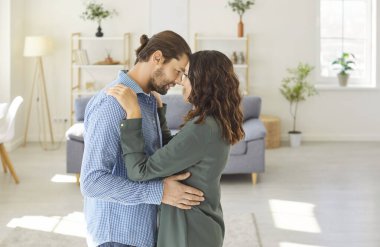 Sevgi dolu çift, sarılma ve bakım, aile modern daireye taşınmayı kutluyor, karı koca birlikte mutlu yaşıyorlar, evliliğin tadını çıkarıyorlar, yeni bir daireye taşınıyorlar, yeni bir hayata başlıyorlar harmonik ilişkiler kuruyorlar.