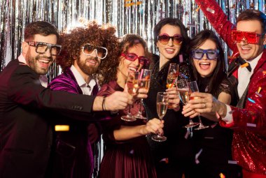 Mutlu arkadaşlar bayramı akşam partisinde kutluyor, şampanya içiyor ve eğlenerek dans ediyor, neşeli anlar yaratıyor bağlantı ve eğlence odaklı neşeli bir ortamda.