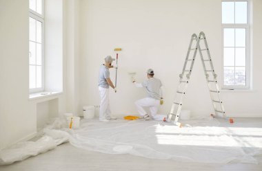 Boyacılar duvar boyası, inşaat işçileri, koruyucu üniforma giyen merdiven kenarındaki profesyonel hizmet hazırlığa, boyamaya, oda tamiri işlerini bitirmeye hazır.