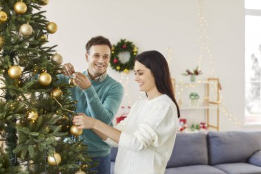 Bir çift Noel ya da yılbaşı ağacı süslemek için evde vakit geçiriyor. Bayram için hazırlanıyorlar, neşeli bir atmosfer yaratırken evdeki ağaca süslemeler ekliyorlar..