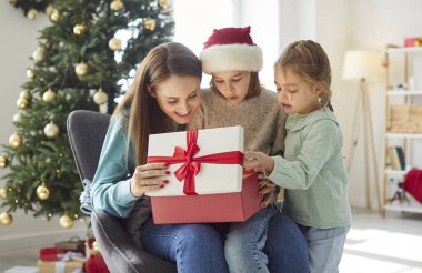 Heyecanlı bir aile, çocuklu bir anne Noel hediyelerini evde birlikte açarken eğleniyor çocuklar geleneksel yeni yıl tatillerini kutluyor.