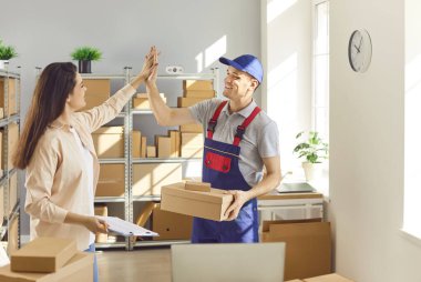 Teslimatta başarılı bir başarı. Neşeli, organize bir depo müdürü ve yükleyici işi beşlik çakarak halletti. İnsanlar parlak aydınlatılmış depo odasındaki karton kutularla çevrili..