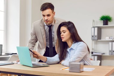 İş adamları, şirket danışmanı laptopta yeni çalışan şirket verilerini gösteriyor, stajyer, erkek, kadın iş arkadaşları sunumu izliyor, mesaj okuyor, masa başında birlikte çalışıyorlar.