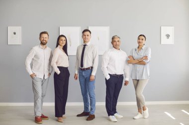 Ofiste bir arada duran mutlu bir iş adamının tam boy portresi. Çeşitli çalışma grupları, takım çalışması, işbirliği ve pozitif çalışma ortamı vurgulanıyor.