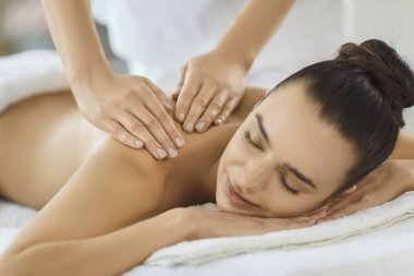 Masseuse performing back massage for pleased woman client during spa treatment, relax care, enhancing pleasure and body therapy in a peaceful salon environment of wellness and comfort.