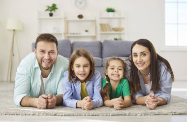 Mutlu dost canlısı bir aile, mutlu bir aile, neşeli bir aile ve sevgili bir kız çocuğu, sıcak zeminde bir oğlan çocuğu, modern iç mekanda sıcak bir halı, gülme, sevinç çığlıkları, aile eğlencesi.