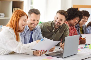 Ofisteki bir toplantıda evrak işleri ve dizüstü bilgisayarda birlikte çalışan mutlu iş adamları takımı. Grup, iş konularını konuşmak ve işbirliği içinde tartışıyor..