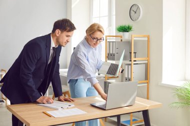 Genç neşeli iş adamları iş yerinde masa başında dizüstü bilgisayar ekranına bakıyor ve şirket finans verilerini tartışırken gülümsüyor. Muhasebeci iş konsepti.