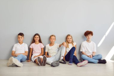 Değişik bir grup öğrencinin portresi sakin gri bir arka planda yan yana oturuyordu. Gülümsemeler, kameraya bakıp birbirlerine yakın arkadaş grupları oluşturan gülümsemelerle mutluluk saçıyor..