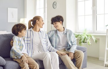 Mutlu anne oğullarıyla vakit geçirir, evdeki kanepede sohbet eder. Ebeveynler ve çocuklar arasındaki yakın bağ ve sevgi, aile ilişkileri ve bağlantı.