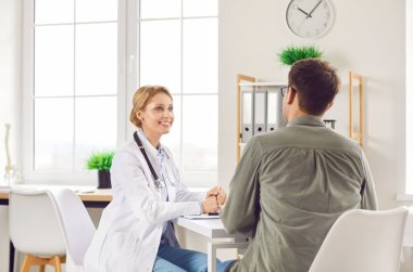 Tıbbi randevuda erkek hastaya danışan, kendinden emin gülümseyen kadın doktor, sağlık sonuçlarını açıklayan, toplantıda tavsiye veren, konuşan, ilgilenen ciddi genç kadın doktor. 