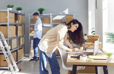 Lojistik ya da dağıtım merkezindeki masada çalışan bir bayan yönetici. Depodaki depoda müşterinin siparişini hazırlayan erkek bir meslektaşla birlikte. Envanter ve teslimat konsepti.