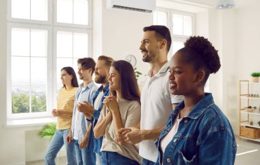 Kendine güvenen, neşeli, genç bir kadının portresi. Sıradan giyinen erkek ve kadınlar. Kapalı kapılar ardında sıralanmış ve gülümsüyorlar. Öğrenciler ya da çalışanlar toplantı üzerine eğitim görüyorlar.
