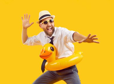 Mutlu ofis çalışanları yaz tatilinde eğleniyor. Neşeli, komik, heyecanlı, sakallı, gömlekli, kravatlı, tatil şapkalı, sarı lastik ördek yüzüklü ve plajda oynayan güneş gözlüklü adam. Stüdyo çekimi