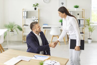 İki mutlu gülümseyen adam ve kadın ofiste el sıkışıyor toplantıyı bitiriyor, başarıyı kutluyor, iş başarısını kutluyor, iyi bir anlaşma yapıyor, kontrat imzalıyor ya da yeni bir çalışanı selamlıyor..