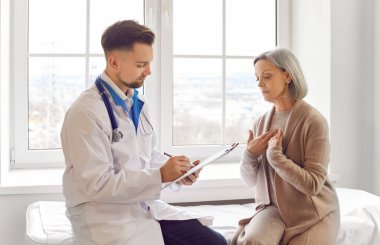 Doktor danışmanlık kadın kıdemli hasta semptomları paylaşıyor, şikayet ediyor, endişeli, sağlık sorunları var. Yaşlı kadın tıbbi bakım için kliniğe gidiyor, tedavi planını tartışıyor, yardım istiyor, gergin.