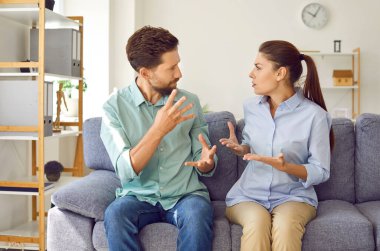 Kızgın genç çift evdeki kanepede oturuyor ve oturma odasında bağırarak tartışıyorlar. Hayal kırıklığına uğramış mutsuz karı koca kavgası. Kötü evlilik, ilişkiler, kavga ve boşanma kavramı.