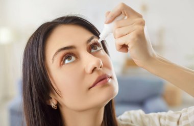 Odaklanmış kadın, alerji, kuru göz, konjonktivit ya da glokom gibi şeylere göz damlası uygular, sağlık ve rahatlama odaklı kişisel ortamlarda görme bakımı için ilaç kullanır..