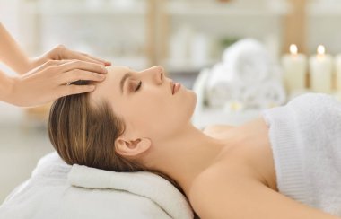 Kozmetikçi doktor güzellik salonundaki spa prosedürleri sırasında kadınlara yüz masajı yapar, iyileşme odaklı profesyonel bir ortamda rahatlama için bakım ve tedaviyi vurgular..