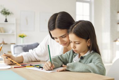 Olumlu ve mutlu anne ve genç kız boş zamanlarını evde resim yaparak, resim çizerek ve masada oturarak geçiriyorlar. Yaratıcılık, aile bağı, eğitim ve paylaşılan faaliyetlerin keyfi.