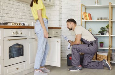 Profesyonel tesisatçı, lavabo, tıkanma sorunlarını çözüyor, kadın müşterisi yanında duruyor, sorunun ne olduğunu açıklıyor, kaliteli mal sağlıyor. Bakım, temizlik ve ev işleri.. 