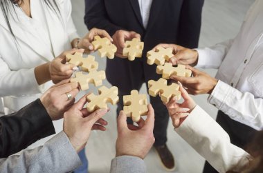 İş adamlarından oluşan yakın plan bir grup takım çalışması ve problem çözme, ahşap yapboz parçaları, işbirliği sembolü, iş birliği. Ortak hedefe ulaşmak için katkıda bulunma kavramı 